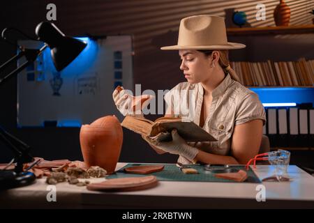 Archäologe, der alte Bücher liest, spät abends im Büro arbeitet und Amphoren studiert Stockfoto