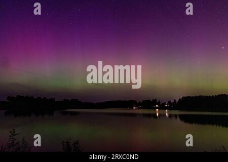 Nachtbild einer riesigen, mehrfarbigen, grünen, leuchtenden Aurora Borealis, Aurora Polaris, auch bekannt als die Nordlichter am Nachthimmel über einem See, L Stockfoto