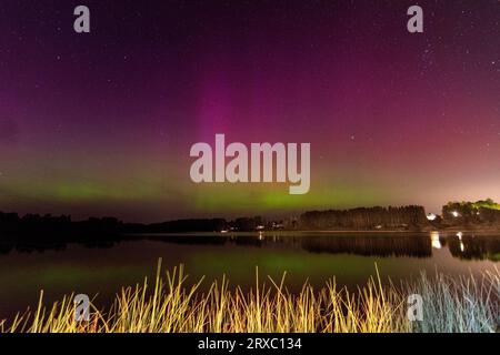 Nachtbild einer riesigen, mehrfarbigen, grünen, leuchtenden Aurora Borealis, Aurora Polaris, auch bekannt als die Nordlichter am Nachthimmel über einem See, L Stockfoto