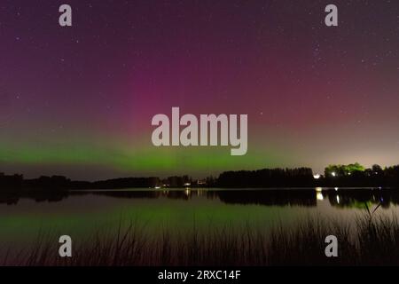 Nachtbild einer riesigen, mehrfarbigen, grünen, leuchtenden Aurora Borealis, Aurora Polaris, auch bekannt als die Nordlichter am Nachthimmel über einem See, L Stockfoto