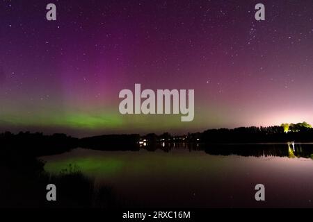 Nachtbild einer riesigen, mehrfarbigen, grünen, leuchtenden Aurora Borealis, Aurora Polaris, auch bekannt als die Nordlichter am Nachthimmel über einem See, L Stockfoto