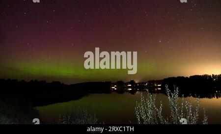 Nachtbild einer riesigen, mehrfarbigen, grünen, leuchtenden Aurora Borealis, Aurora Polaris, auch bekannt als die Nordlichter am Nachthimmel über einem See, L Stockfoto