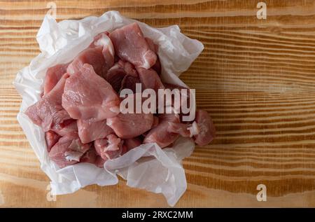 Schweineschnitzel verpackt in weißem Papier auf einem Holztisch. Stockfoto