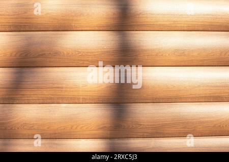 Schirm aus Holz. Holzhintergrund. Licht auf der Oberfläche. Braune Verkleidung aus Holz imitierender Plastik. Stockfoto