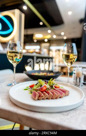 Thunfisch-Tataki-Salat mit Salat, Kirschtomaten und Avocado auf einem Marmortisch in einem Restaurant. Hochwertige Fotos Stockfoto