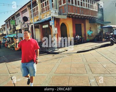 George Town, Penang, Malaysia - 23. Januar 2023: Asiatischer Touristiker fotografiert mit Smartphone auf Selfie-Stick auf der Carnarvon-Straße. Stockfoto