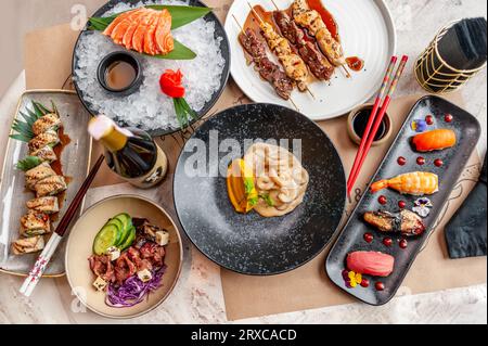 Auswahl an japanischen Gerichten: Sushi, Nigiri, Sashimi, Yakitori und eine Flasche Sake Stockfoto