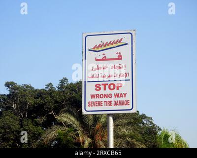 Ein Warnschild auf Arabisch und Englisch, Übersetzung arabischer Wörter ( Stopp, falsche Richtung, schwerer Reifenschaden ) als Warnung vor einer Stachelsperre an Stockfoto