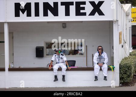 September 2023: Zwei Marshals sitzen an der Wand am Eingang der Gruben beim Goodwood Revival Race Meeting. Stockfoto