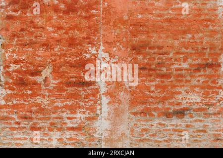 Alte Ziegelwand mit abblätternder roter Farbe und verwittertem Altmörtel als Hintergrund mit einzigartiger Textur und Muster, abstrakter Grunge-Hintergrund Stockfoto