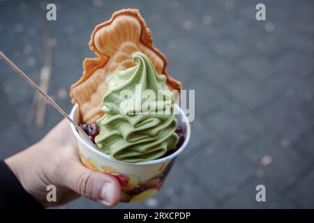 Halten Sie eine Tasse Matcha-Grüntee mit weichem Eis mit Taiyaki, japanischem Fischkuchen und roten Bohnen auf der Straße. Stockfoto