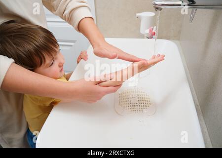 Mutter und Kind waschen sich die Hände mit Seife in der Badewanne. Kind im Alter von zwei Jahren (zweijähriger Junge) Stockfoto