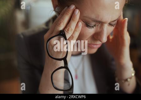 Nachhaltiger Arbeitsplatz. Moderne Geschäftsfrau im modernen grünen Büro mit Brille und kabellosen Kopfhörern. Stockfoto