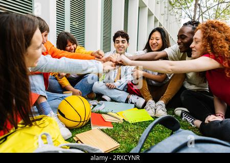 Junge Studenten, die mit der Faust die Zusammenarbeit und Teamarbeit zeigen Stockfoto