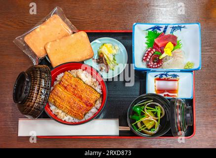 Japanisches Menü mit einer Schüssel Unagi-Aalfilets, gegrillt im Kabayaki-Stil, garniert auf gedämpftem Reis mit Sashimi aus Tintenfisch und Thunfisch, Suimono Stockfoto