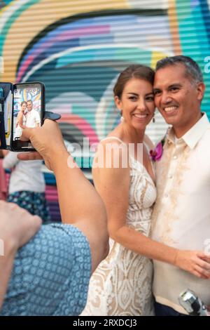 Ein Hochzeitsgast macht ein Foto von einer Braut und einem Bräutigam am Hochzeitsempfang. Stockfoto