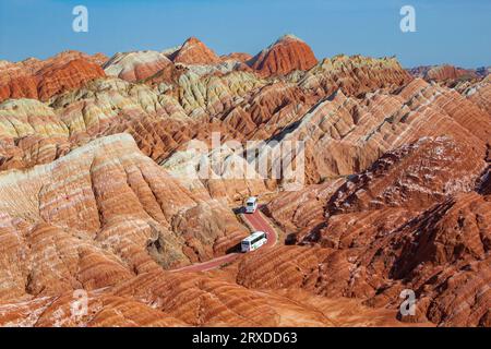 Kurvige Straße durch die bunten Regenbogenberge. Die chinesische Landschaft auf der Seidenstraße. Wunderschöner Sonnenuntergang im Zhangye Danxia National Geological Park, Gan Stockfoto