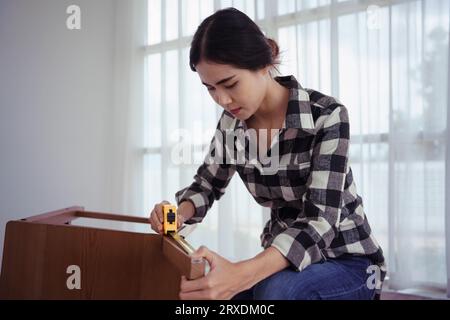 Frauen messen die Länge des Stuhls mit Maßband während der Montage und Renovierung von Stuhlmöbeln. Stockfoto