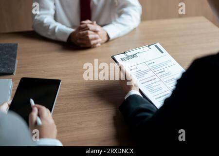 HR-Manager Frau liest Lebenslauf und schreibt Daten während des Bewerbungsgesprächs mit einem männlichen Kandidaten auf das Tablet. Stockfoto