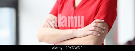 Zugeschnittenes Bild einer Frau in rotem Hemd, die am Fenster steht. Stockfoto