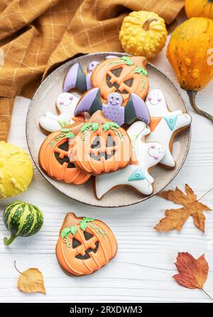 Bunte selbstgemachte Halloween-Kekse auf weißem hölzernem Hintergrund. Stockfoto