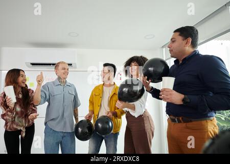 Ein Team von Entwicklern, das eine Partei im Büro des IT-Unternehmens hat Stockfoto