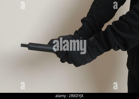 Nahaufnahme der männlichen Hand, die nach dem Schuss seine Pistole nachlädt. Isoliertes Bild auf grauem Hintergrund Stockfoto