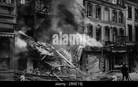 Geschäfte in Flammen in Brüssel, Belgien nach einem deutschen Luftangriff auf die Stadt, während des Zweiten Weltkriegs. Die Bombardierung dauerte vom 11. Bis 17. Mai 1940, begründet mit der Tatsache, dass alliierte Militäraktivitäten in der Stadt beobachtet wurden. Stockfoto