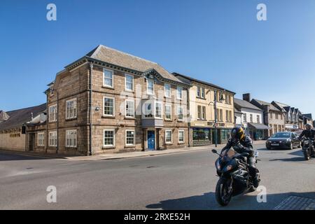3. Juni 2023: Okehampton, Devon, UK - Rathaus und historische Gebäude in der Okehampton High Street, auch Radfahrer fahren durch. Stockfoto