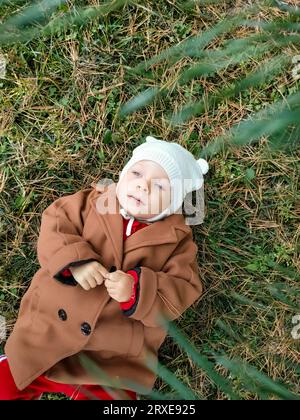 Ein kleines Kind liegt auf dem Boden und lächelt. Draufsicht. Das Konzept der Herbstblätter für Kinder. Ein Lächeln im Gesicht eines Kindes. Ein kleines Kind in einem Stockfoto