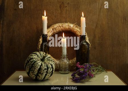 Ein Stillleben mit brennenden Kerzen, einem Kranz und trockenen Blumen Stockfoto