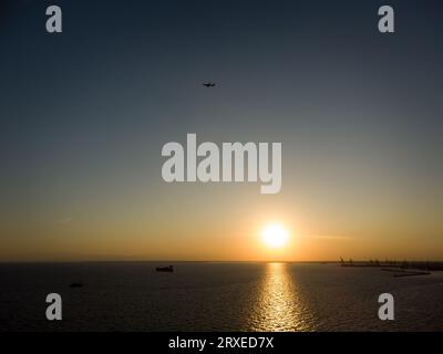 Griechenland, Thessaloniki, september 2023. Schiff und Passagierflugzeug bei Sonnenuntergang in der Bucht von thessalonica in der Nähe des Hafens. Stockfoto