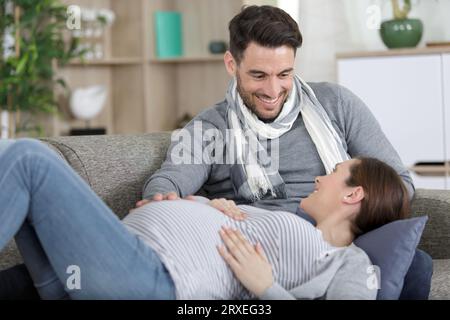Schwangere Frau und gutaussehender Mann, der auf dem Sofa liegt Stockfoto