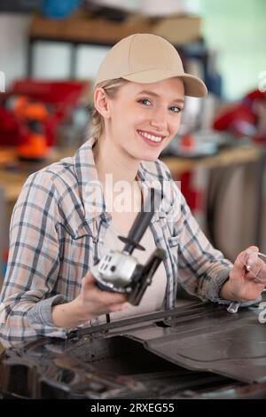 Glückliche Mechanikerin, die ein Auto repariert Stockfoto