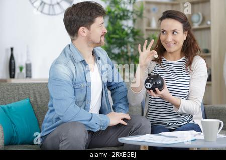 Glückliches Paar, das Münze in eine Spardose steckt Stockfoto
