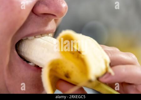 Eine Erwachsene Frau isst eine Banane, Nahaufnahme. Stockfoto