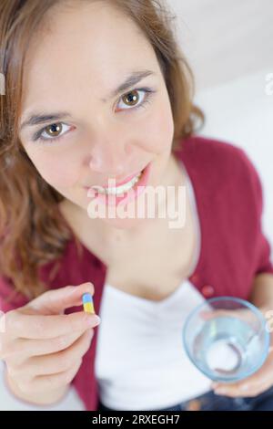 Lächelnde Frau, die Tabletten und Trinkwasser isst Stockfoto