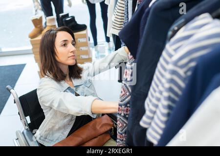 Frau im Rollstuhl, die sich in einem Laden Tücher aussucht Stockfoto