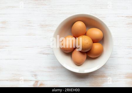 Teller mit braunen Hühnereiern auf Holztisch. Braune Eier in Schüssel auf Holzgrund. Bio-Eier aus Freilandhaltung in Schüssel. Natürliches gesundes Lebensmittelkonzept. T Stockfoto