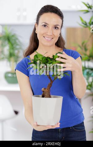 Schönes Mädchen, das mit einem Bonsai in den Händen steht Stockfoto