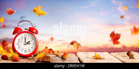 Rückfallzeit - Sommerzeit Ende - Wecker Bei Sonnenaufgang Mit Blättern - Rückkehr Zur Winterzeit Stockfoto