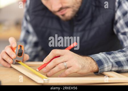 Handwerker, der Holzbilderrahmen misst Stockfoto