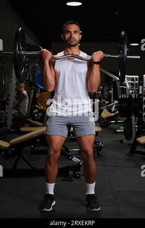 Starker hispanischer Mann, der eine Langhantelwelle für Bizepsstärke in einem Fitnessstudio macht. Stockfoto