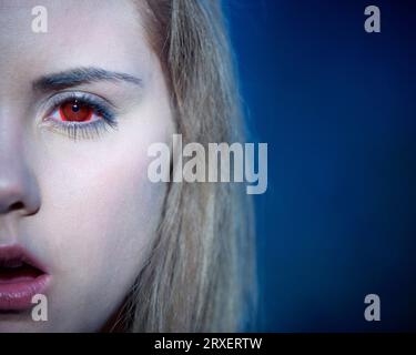 Abgeschnittene Vorderansicht einer Frau mit roten Kontaktlinsen, die auf die Kamera starrt. Stockfoto
