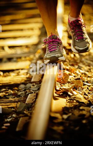Vorderansicht der Beine einer Frau, die auf einer Eisenbahnstrecke spazieren. Stockfoto