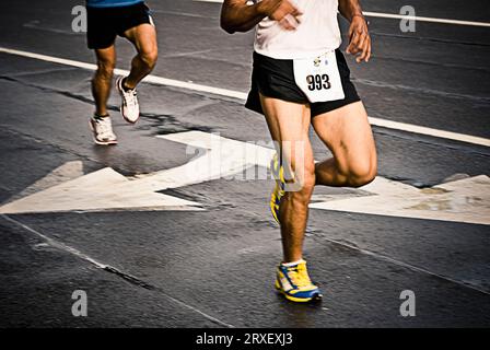 Zwei männliche Laufbeine mit weißen Pfeilen auf der Straße. Herndon, VA. Stockfoto