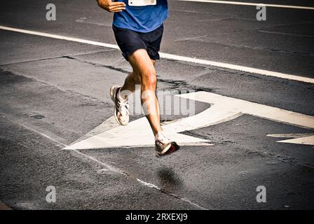Ein Mann in blauem Hemd, der auf der Straße an weiß bemalten Pfeilen vorbeiläuft. Herndon, VA. Stockfoto