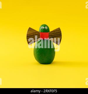 Die Elegante Mr. Avocado. Lustiges Minimal-Konzept aus frischer Avocado auf hellgelbem Hintergrund. Naturmodedesign. Stockfoto