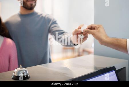 Pärchen, Die Im Hotel Nachfragen Und Den Schlüssel Vom Rezeptionisten In Der Halle Nehmen, Ausgehändigt Stockfoto