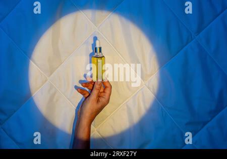 Frau Hand auf dem Hintergrund einer Decke im Licht des Mondes mit Tropfer mit Schlaföl. Schlaflosigkeit bekämpfen Stockfoto